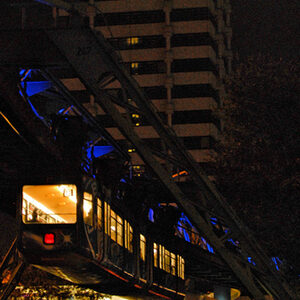 Die Schwebebahn vor dem Sparkassenhochhaus bei Nacht